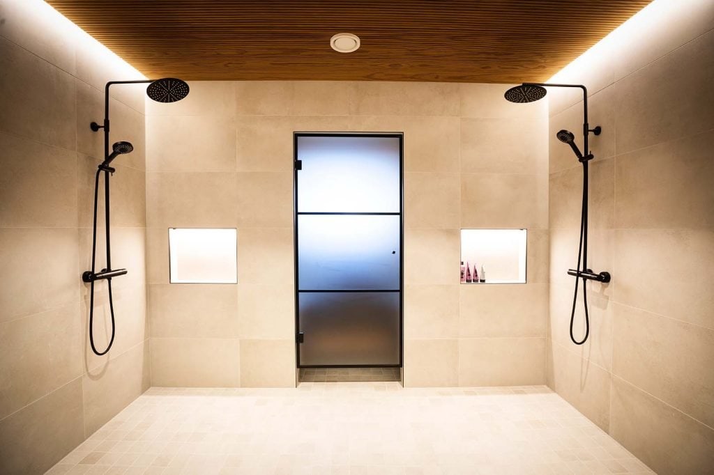 Kuvassa rakennustyömaa, jossa kaksi suurta nosturia asettamassa elementtejä suureen rakennukseen, taustalla pilvinen taivas.